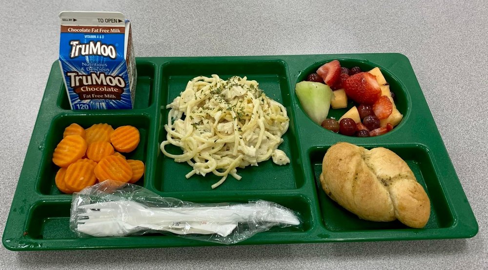 Tray of food with carrots, pasta, fruit, and roll